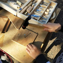 Boy hammering nail in wood with child size real hammer