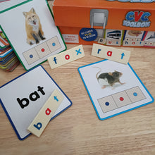 Educational CVC word cards with animals and letters on a wooden surface.