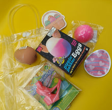 Assorted novelty items including a box of 'Dip 'n Melt' eggs, a pink toy, and a plastic bag on a yellow background.