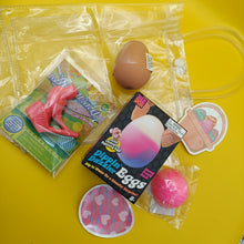 Assorted novelty items including a pink flamingo, egg-shaped product, and plastic bag on a yellow background
