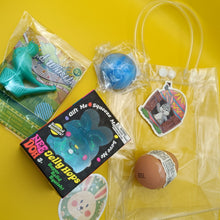 Collection of novelty items including a blue jelly hopper, a brown egg, and a clear bag with a tag on a yellow background.
