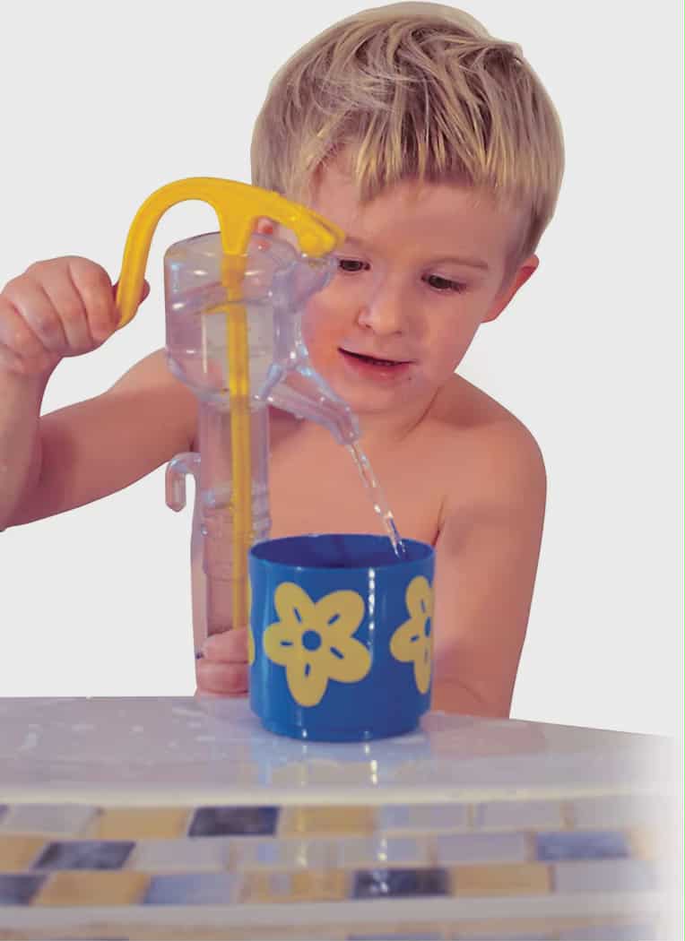 Child pouring water from a yellow and clear pitcher into a blue cup with yellow flowers on a white background