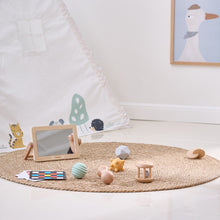 Children's toys on a woven mat in a room with a mirror and framed picture on the wall.