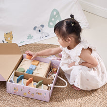 Child playing with wooden blocks in a box on a carpeted floor.