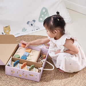 Child playing with wooden blocks in a box on a carpeted floor.
