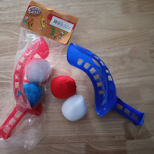 Toy set with red and blue water ball launcher rackets and balls on a wooden surface, featuring 'Super Toys' packaging.