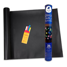 Black chalkboard table runner with colorful chalk sticks and a roll of chalkboard paint on a white background