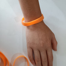 Hand wearing an orange bracelet on a white background