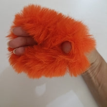 Orange fluffy object held by a hand on a white background