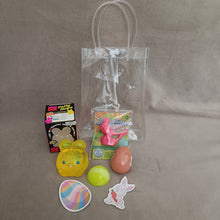 Clear plastic bag with Easter-themed items including a yellow bunny, green egg, pink egg, and a colorful Easter egg design on a gray background.