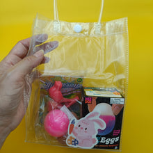 Clear plastic bag with Easter-themed items including a pink egg and bunny on a yellow background