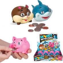 Toy piggy banks shaped like a pig, shark, and chipmunk with coins around them, and a hand holding a pink piggy bank.