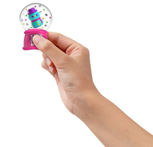 Hand holding a small snow globe with a colorful toy inside on a white background