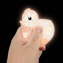 Hand holding a glowing duck-shaped night light against a black background