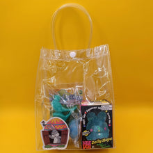 Clear plastic bag with toys and a book on a yellow background