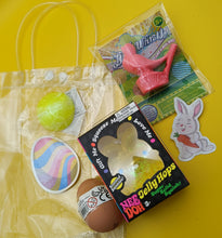 Assorted toys and items including a jelly hopper, a pink bird toy, and a yellow ball on a yellow background.
