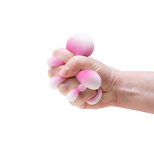 Hand holding a pink and white stress ball against a white background