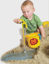 Child playing with sand toys including a yellow bucket and shovel on a sandy surface.