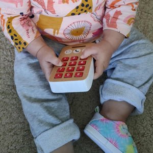 Baby playing with wooden telephone buttons